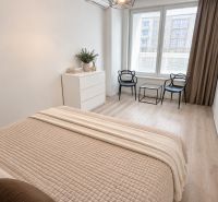 Helles Schlafzimmer in einer 2-Zimmer-Wohnung mit Holzboden und einfacher Einrichtung.
