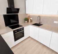 Küche in einer 2-Zimmer-Wohnung mit weißen Schränken, Kochfeld und Holzboden.