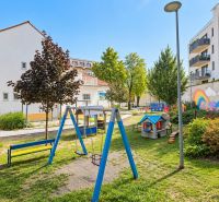 Ein Kinderspielplatz umgeben von Gebäuden mit bunten Wandmalereien in der Sancova-Straße.