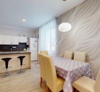Küche in einem Einfamilienhaus mit Kücheninsel und Esstisch mit modernen Stühlen.