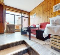 Wohnzimmer in einem Einfamilienhaus mit holzverkleideten Wänden und gefliestem Boden.