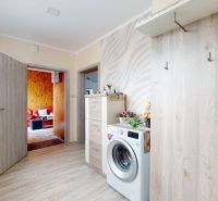 Innenraum eines Einfamilienhauses mit Waschmaschine, Kommode und Boden in Holzoptik.
