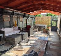 Eine verglaste Terrasse eines Einfamilienhauses mit Rattanmöbeln und einem Whirlpool.