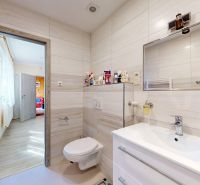 Ein Badezimmer in einem Einfamilienhaus mit Keramikfliesen und einem Boden in Holzoptik.