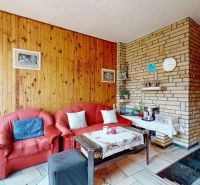 Wohnzimmer mit Holzvertäfelung, Kamin und rotem Sofaset in einem Einfamilienhaus.