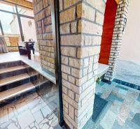 Innenraum eines Einfamilienhauses mit steinverkleideter Treppe und verglaster Wand.