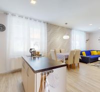 Küche und Wohnzimmer in einem Einfamilienhaus mit Holzboden und hellen Möbeln.