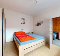 Schlafzimmer in einem Einfamilienhaus mit Bett, Kleiderschrank und Wanddekorationen.