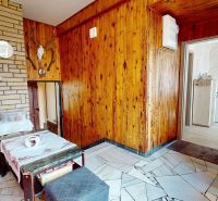 Innenraum eines Einfamilienhauses mit Holzverkleidung, Sofa und Kaffeemaschine an der Steinwand.