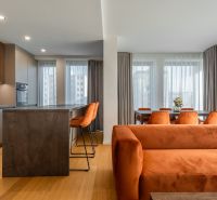 Innenraum mit Holzboden, orangefarbenem Sofa und Esstisch. Wohnungsbau.