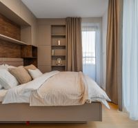 Helles Schlafzimmer mit beigen Vorhängen, Regalen und einem Boden mit Holzdekor im Projekt Wohnungsbau.