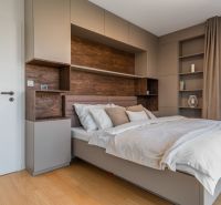 Schlafzimmer in einer Wohnung mit modernen Schränken und einem Boden in Holzoptik.