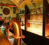 Eine Bar-Theke in gastronomischen Räumlichkeiten mit einer Ziegelwand und Messingzapfhähnen.