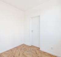 Ein Zimmer mit weißen Wänden und einem Boden in Holzoptik, eine 2-Zimmer-Wohnung.