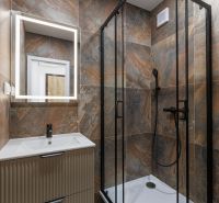 Badezimmer mit LED-Spiegel und Duschkabine in einer 2-Zimmer-Wohnung.