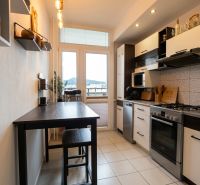 Küche in einer 2-Zimmer-Wohnung mit dunklem Tisch und hellem Boden.