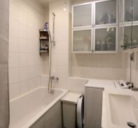 Badezimmer in einer 2-Zimmer-Wohnung mit Badewanne, Schränken und Waschmaschine.
