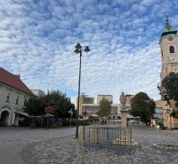 Geschäftsräume in Topoľčany mit einem gepflasterten Platz und einer Kirche im Hintergrund.