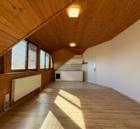 Dachbodenraum in einer 3-Zimmer-Wohnung mit Küchenzeile und Holzboden.