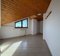 Ein Dachzimmer in einer 3-Zimmer-Wohnung mit einer Holzdecke und Fliesenboden.