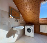 Badezimmer mit Waschmaschine, Waschbecken, Boden mit Holzdekor, Dachfenster.