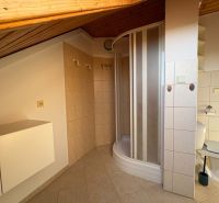 Badezimmer in einer 3-Zimmer-Wohnung mit Eckdusche und Fliesen in Holzoptik.