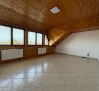Ein sauberes Zimmer mit Holzelementen, Heizkörpern und großen Fenstern in einer 3-Zimmer-Wohnung.
