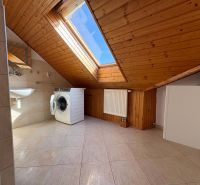Dachboden-Badezimmer mit Waschmaschine, Dachfenster, Keramikfliesen und Holzverkleidung.