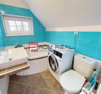 Badezimmer in einer 2-Zimmer-Wohnung mit Waschmaschine, Waschbecken und türkisfarbenen Fliesen.