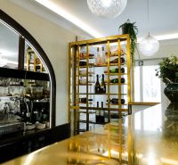 Eleganter Weinkeller und Bar in Geschäftsräumen mit moderner Beleuchtung und goldenen Details.