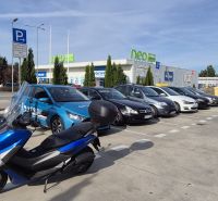Parkplatz mit Autos und einem Motorrad beim Einkaufszentrum in Malacky in der Javorová-Straße.