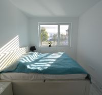 Helles Schlafzimmer mit großem Fenster, Bett und Nachttischen in einer 3-Zimmer-Wohnung.