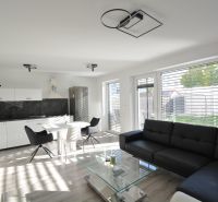 Helles Wohnzimmer mit Küche in einer 3-Zimmer-Wohnung, Sofa, Esstisch, Boden mit Holzdekor.