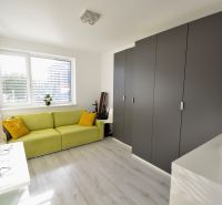 Helles Wohnzimmer in einer 3-Zimmer-Wohnung mit Holzboden und Kleiderschrank.