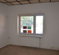 Büros mit weißen Wänden und einem Boden in Holzoptik, ein Fenster mit Heizkörper ist zu sehen.
