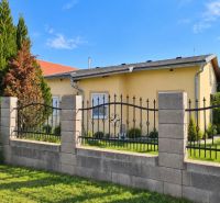 Ein Einfamilienhaus in Martovce mit einem Garten, umgeben von grünen Bäumen und einem Zaun.
