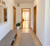 Flur in einem Einfamilienhaus mit Fliesen, einer Schuhbank und einem Spiegel.