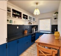 Eine Küche in einem Einfamilienhaus mit stilvollen blauen Schränken und einem gemütlichen Holztisch.