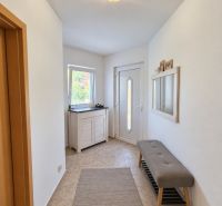 Ein heller Eingangsbereich in einem Einfamilienhaus mit einer Bank und einem Spiegel an der Wand.