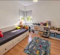Kinderzimmer in einem Einfamilienhaus mit Bett und Stauraum, Boden mit Holzdekor.