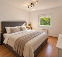 Schlafzimmer im Einfamilienhaus mit großem Bett und Boden in Holzoptik.