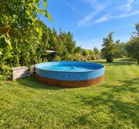 Draußen in Martovce bei einem Einfamilienhaus, ein runder Pool auf dem Rasen, umgeben von Grün.