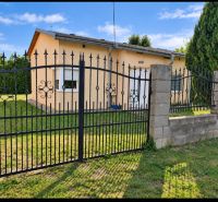 Ein Einfamilienhaus in Martovce mit einem Rasen-Grundstück und einem Metallzaun.