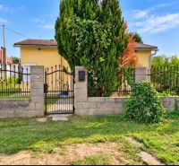 Ein Einfamilienhaus in Martovce mit einem Vorgarten und einem Metalltor, umgeben von einer Hecke.