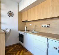 Küchenzeile in einem Einzimmerapartment mit Holzboden und eingebauten Geräten.