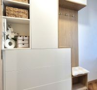 Innenraum eines Einzimmerapartments mit Holzmöbeln, Dekorationen und einer Pflanze auf dem Boden mit Holzdekor.
