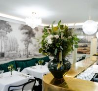 Innenraum von Geschäftsräumen mit goldener Bar, Blumendekoration und eleganten Tischen.