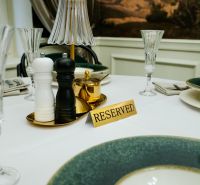 Ein reservierter Tisch mit Tischdecke in Geschäftsräumen, enthält Gewürzstreuer und elegante Gläser.