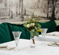 Ein elegant gedeckter Tisch mit einem weißen Tischtuch, einer Vase mit Blumen und Kristallgläsern.