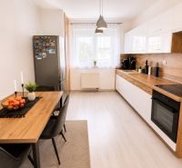Küche in einer 2-Zimmer-Wohnung mit Holzboden, Esstisch und Geräten.